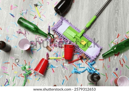 After party mess with empty bottles, plastic cups, confetti, and a mop on the floor