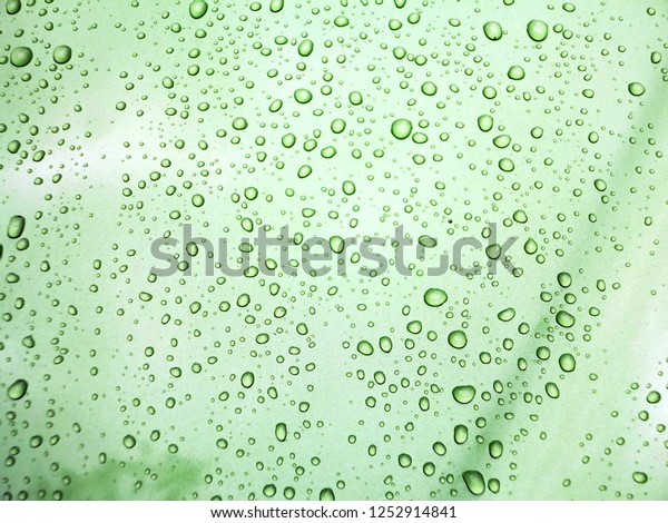 After raining\
the beautiful rain droplets were left on some parts of green car\
surfaces with the reflections.\
