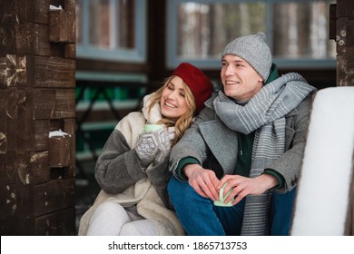 After spending a day off in the woods in winter, a young couple basks in a summer house and drinks a hot drink from mugs. - Powered by Shutterstock