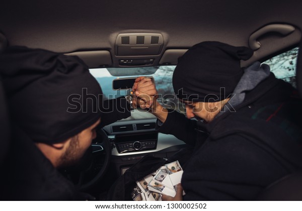 After the successful bank robbery, the thieves are\
sitting in the car showing off their money and celebrating the win\
over the law they had.