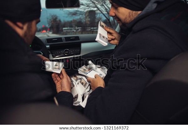 After the successful bank robbery, the thieves are\
sitting in the car showing off their money and celebrating the win\
over the law they had.