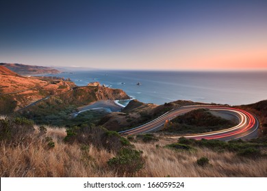 After sunset on the Pacific Ocean looking down the famous highway 1 as evening traffic travels in both directions. 