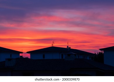 After sunset over the roofs of the houses in the town. Colorful clouds.