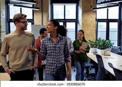 After Team Meeting. Two Young Diverse Business People, Male And Female Coworkers Talking About Something While Walking In The Modern Office