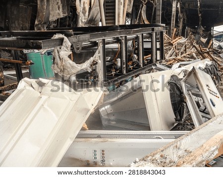 The aftermath of a severe fire has left industrial machinery and building structures in a state of complete disarray and ruin
