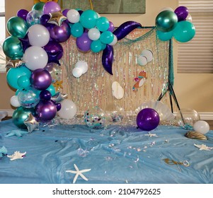 The aftermath of a smash cake photoshoot. Mermaid theme photo background with mermaid tail with fin garland.