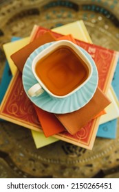 Afternoon Tea In Square Teal Teacup And Saucer On Stack Of Books On Brass Tray Table