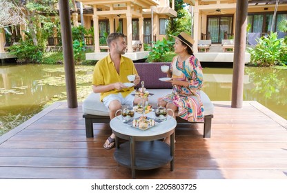 Afternoon Tea At A Water Pond, High Tea In A Tropical Garden In Thailand. Couple Of Men And Women Having High Tea In A Tropical Garden