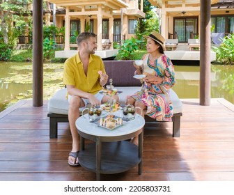 Afternoon Tea At A Water Pond, High Tea In A Tropical Garden In Thailand. Couple Of Men And Women Having High Tea In A Tropical Garden