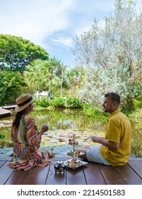 Afternoon Tea At A Water Pond, High Tea In A Tropical Garden In Thailand. Couple Of Men And Women Having High Tea In A Tropical Garden