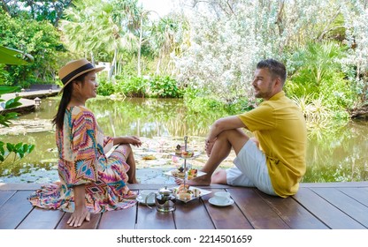 Afternoon Tea At A Water Pond, High Tea In A Tropical Garden In Thailand. Couple Of Men And Women Having High Tea In A Tropical Garden