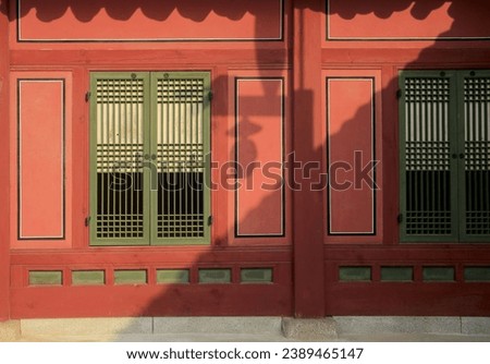 Afternoon view of sunlight and shadow on window door and red wall of a tiled house at Deoksugung Palace of Jeong-dong near Jung-gu, Seoul, South Korea
