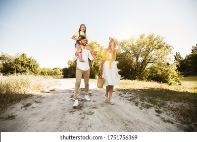 After-Quarantine Walk. Happy Family Walking In Countryside Spending Summer Day Outside Near River, Father Carrying Little Daughter. Full-Length