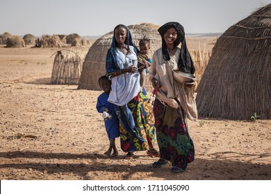 Agadez, Niger - September 2013: African  Family Djerba Tribe In Traditional Colorful Clothes In Front Of Their House In Sahara Desert On The Boarder Of Niger And Algeria 