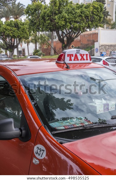 AGADIR, MOROCCO - MARCH 03,\
2016: Detail of a small red taxi in front of the hotel zone in the\
city