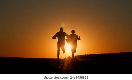 Against the backdrop of the setting sun, two businessmen's silhouettes dance merrily, with a tablet in one man's hand.