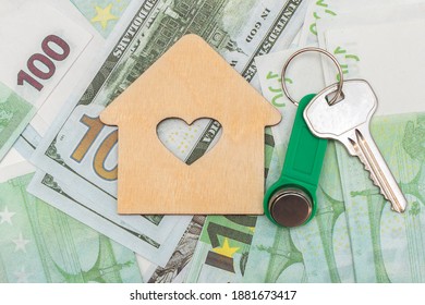 against the background of euro and dollar banknotes lies a house and keys. The concept is home purchase, mortgage, affordable housing. The goal is to acquire real estate. Close-up, horizontal photo.