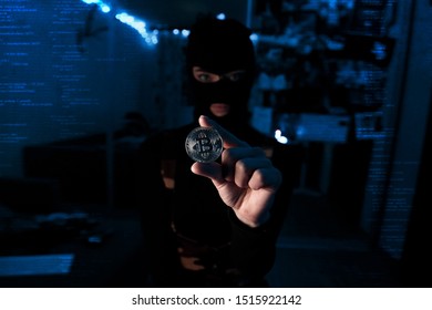 Against the background of neon and a digital code, a hacker stands in a balaclava with crypto currency in his hand