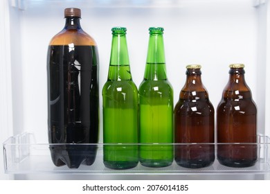 Against The Background Of A White Refrigerator Door, Bottles Of Beer And Kvass Are On The Shelf, Close-up