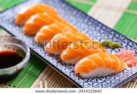 Against background of wooden table is rectangular plate of maki sushi set with nigari rolls, complemented with wasabi Stock photo © 