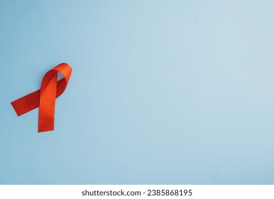 Against a blue backdrop, a red ribbon serves as a symbol of AIDS awareness, a vital cause. This isolated cut-out design embodies the essence of support and unity in the campaign against HIV. - Powered by Shutterstock