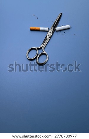 Against a blue background, a pair of scissors and a cigarette cut in half.
