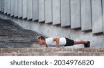 Against building exterior. Young man in sportive clothes have workout outdoors at daytime.