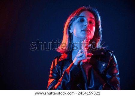 Against dark blue background. Cool young woman portrait in neon colors.