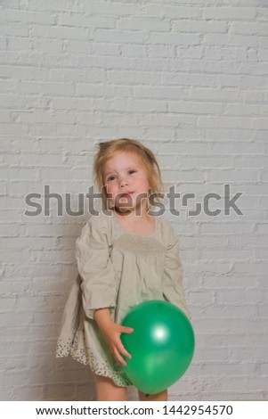 the against a white brick wall sad girl with a green balloon