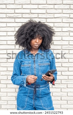 Similar – Serious black woman with afro hair looking at her smart phone outdoors.