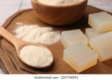 Agar-agar jelly cubes and powder on wooden board, closeup - Shutterstock ID 2257760951