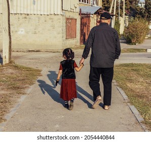 Age Contrast. An Old Man And A Granddaughter On The Sidewalk Of The City.                            