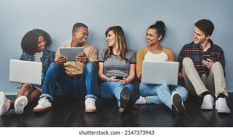 The Age Of Digital Citizenship. Studio Shot Of A Group Of Young People Using Wireless Technology Against A Gray Background.