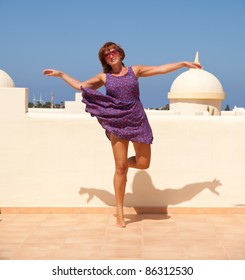 Age Doesn't Matter - Tanned, Fit Middle-aged Woman Dances On The Sunroof In Short Flared Dress