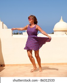 Age Doesn't Matter - Tanned, Fit Middle-aged Woman Dances On The Sunroof In Short Flared Dress