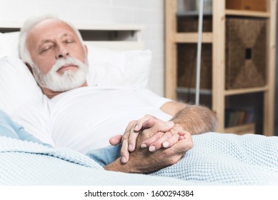 Age, holidays, relax, safeness and people concept - happy senior man sleeping on pillow. Cropped wifes hand. Closeup picture