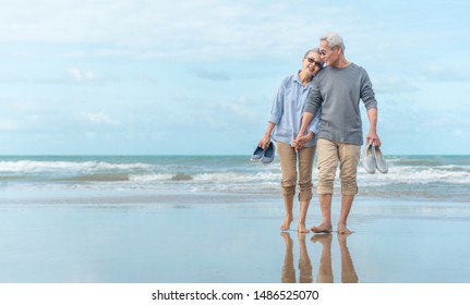 Age, Travel, Tourism and people concept - happy senior couple holding hands and walking on summer beach - Powered by Shutterstock