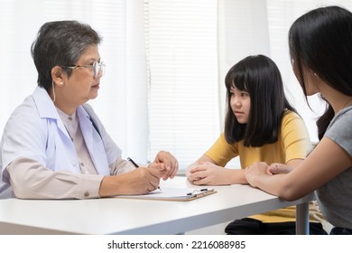 Aged Asian Physician Psychiatrist, General Woman Doctor Consulting Concerned Symptom With Patient Girl, Child At The Appointment At Clinic, Hospital. Health Care, Check Up Medical.