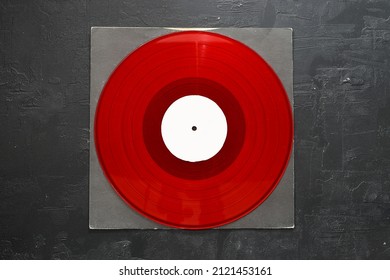 Aged black paper cover and red vinyl LP record isolated on stone background
