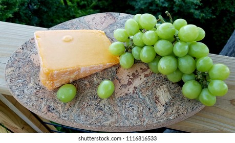 Aged Cheddar Cheese Wedge With Large Green Grape Bunch On A Serving Platter, Close Up