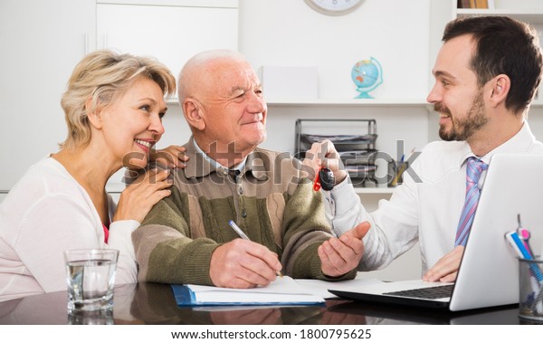 Aged couple\
signing papers for new car in\
bank