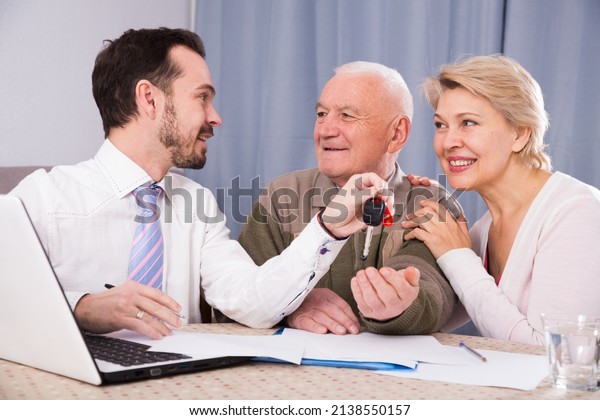 Aged couple\
signing papers for new car at\
home