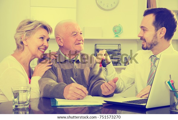 Aged couple\
signing papers for new car in bank\
