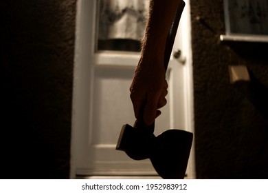 Aged dark and spooky photo of person approaching door holding axe