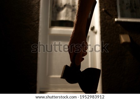 Aged dark and spooky photo of person approaching door holding axe