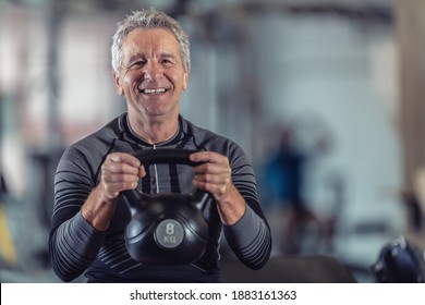 Aged But Fit Male Lifting Dumbells Working Out In A Fitness Center.