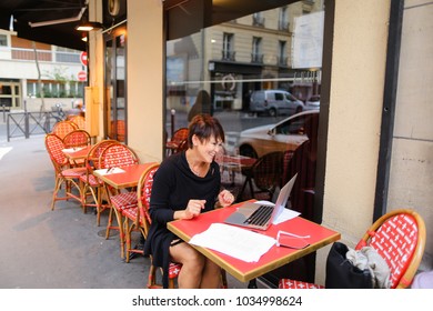 Aged grandmother sitting with laptop in outdoor cafe and have conversation  with grandchildren by videomessanger . Relatives not communicate for long time, and lady looking very happy. Female smilin