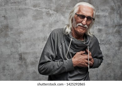 Aged Gray Haired Caucasian Male Pensioner Holds His Chest In Pain From Heart Attack. Grandfather In Glasses With Mustache Got A Stroke