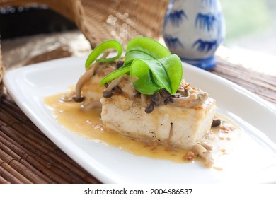 Aged, layered tofu topped shimeji mushrroms and opened snow pea pods