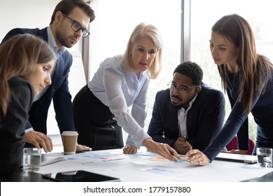 Aged leader young teammates discuss financial report at meeting, serious focused workers involved in data learn, do research analysis of statistics, work together on project, search solutions concept - Powered by Shutterstock